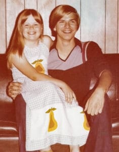 Cherie and Scott in 70s attire, sitting in a 70s style basement.